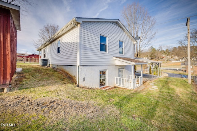 rear view of property featuring a lawn, cooling unit, and fence