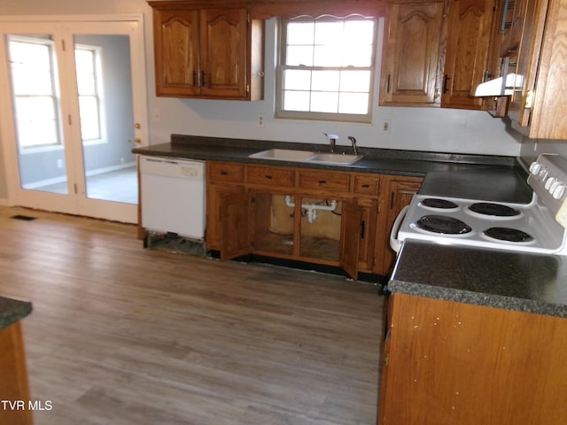 kitchen featuring dishwasher, electric range, brown cabinetry, and a sink