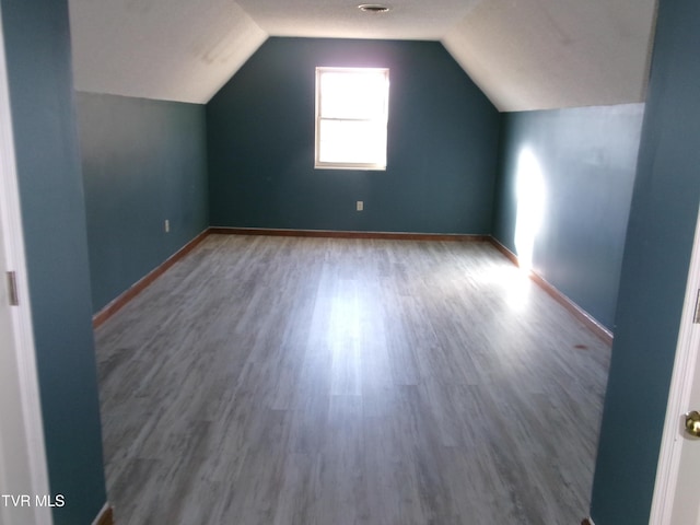 bonus room with lofted ceiling, baseboards, and wood finished floors