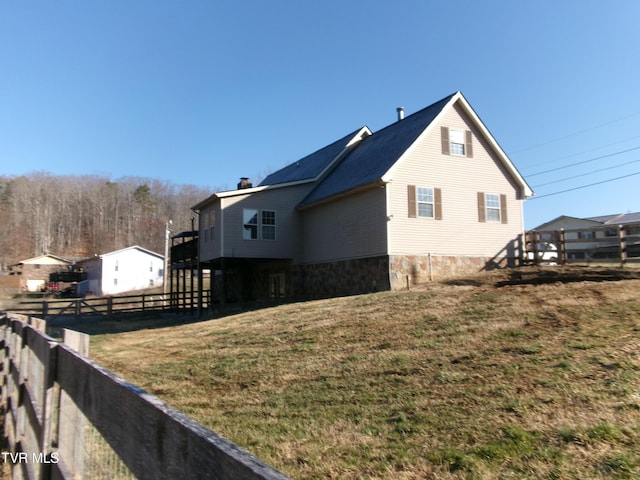 view of home's exterior with a lawn, a chimney, and fence