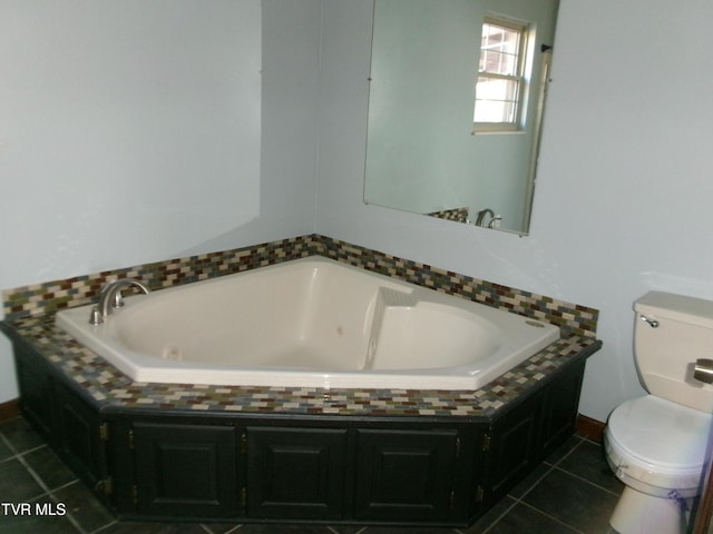 full bathroom featuring a tub with jets, toilet, and tile patterned floors