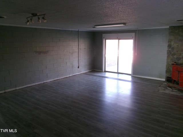 unfurnished living room with dark wood-style floors, concrete block wall, and a textured ceiling