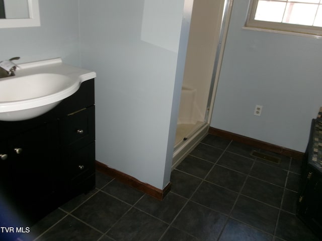 bathroom with a shower stall, tile patterned flooring, baseboards, and vanity