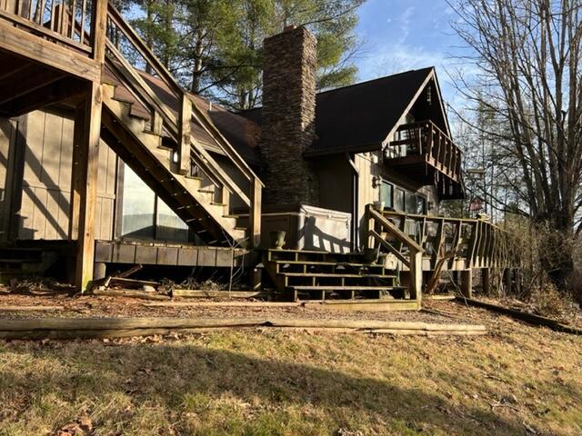 view of side of home with a chimney, stairway, and a wooden deck