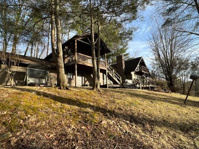 rear view of house featuring stairs, a deck, and a lawn