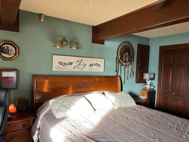 bedroom with a textured ceiling, a closet, and beam ceiling