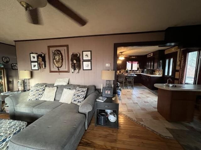 living area with a ceiling fan and stone finish floor