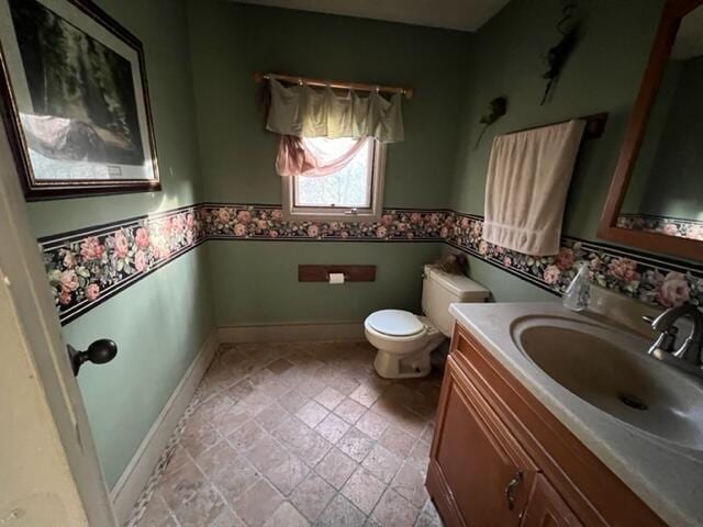 bathroom featuring a wainscoted wall, vanity, toilet, and baseboards