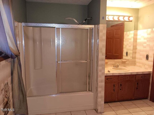 bathroom featuring shower / bath combination with glass door, vanity, tile walls, and tile patterned floors