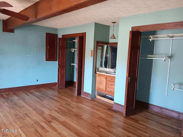 unfurnished bedroom featuring a textured ceiling, light wood finished floors, and baseboards