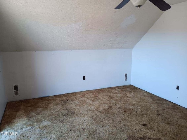 bonus room featuring lofted ceiling, carpet, visible vents, and a textured ceiling