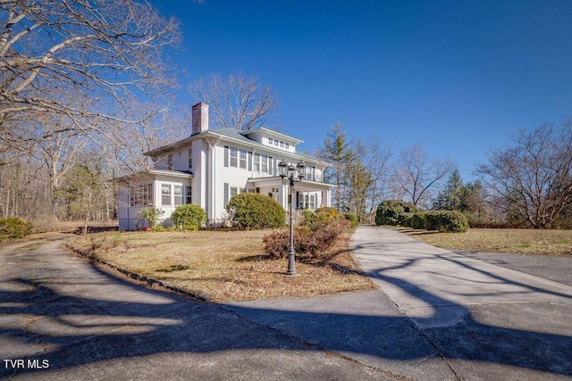 view of side of property featuring driveway and a chimney