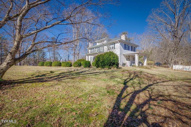 view of property exterior featuring a chimney, fence, and a yard