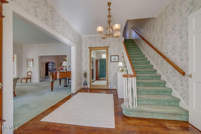 entrance foyer featuring stairs, ornamental molding, wood finished floors, and wallpapered walls