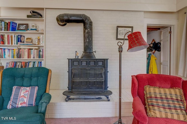 sitting room featuring a wood stove, brick wall, and carpet flooring