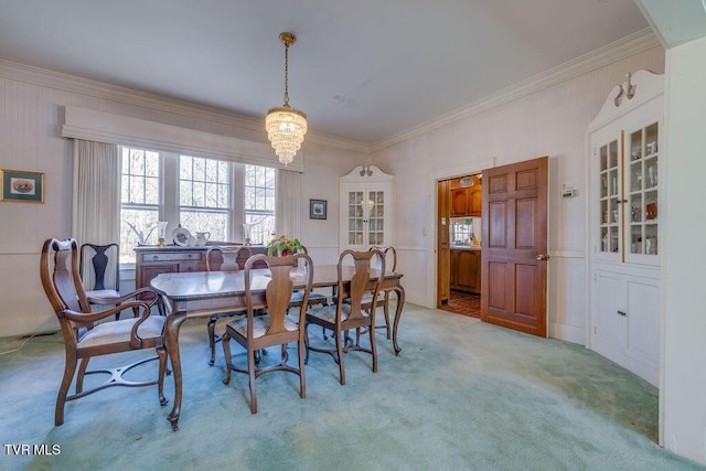 dining area with light carpet, ornamental molding, and a chandelier