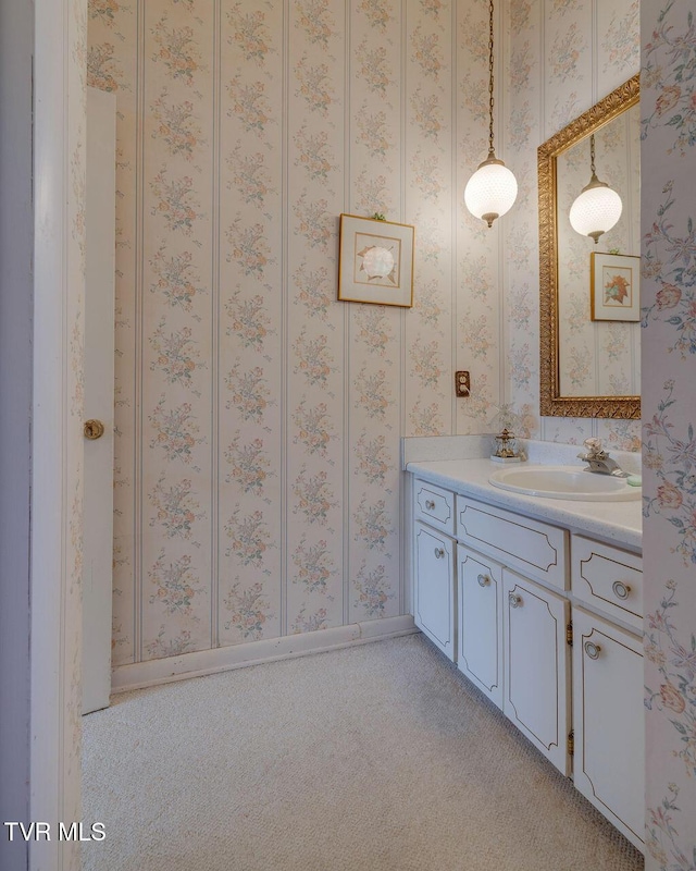 bathroom featuring baseboards, vanity, and wallpapered walls