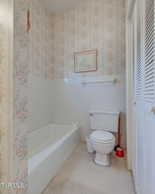 full bath with toilet, wallpapered walls, tile walls, and wainscoting