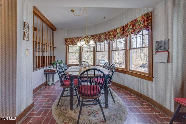 dining room with wallpapered walls, baseboards, brick floor, and a chandelier