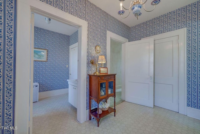 hallway with wallpapered walls, baseboards, a notable chandelier, and tile patterned floors