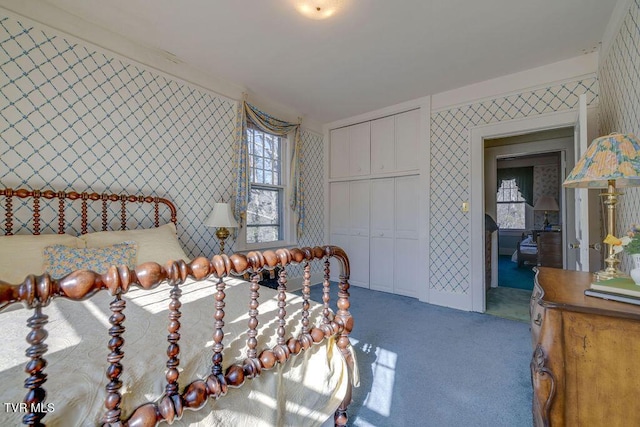 carpeted bedroom featuring a closet and wallpapered walls