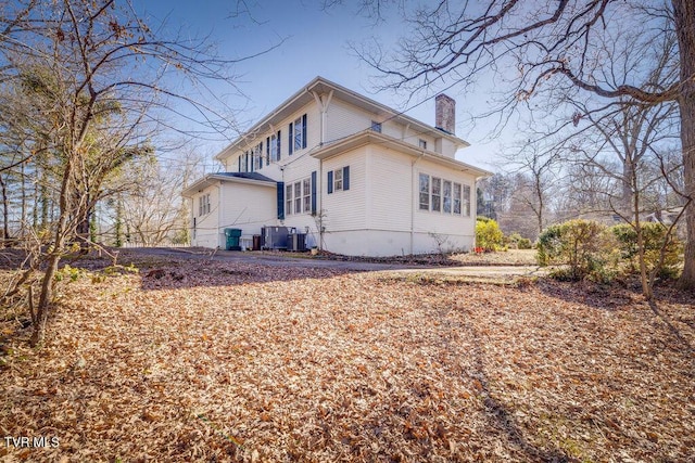 view of side of home with central air condition unit and a chimney