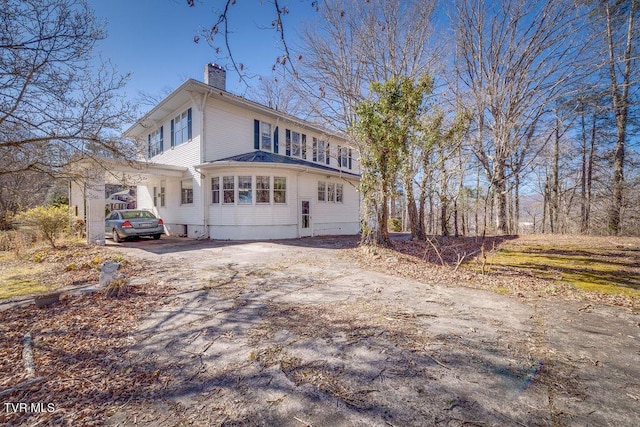 view of side of home featuring aphalt driveway and a chimney