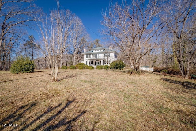 view of front of home featuring a balcony, a chimney, and a front yard