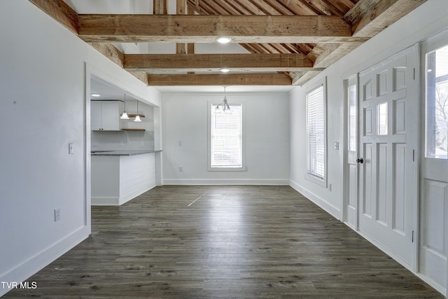 interior space featuring dark wood-style flooring, baseboards, beam ceiling, and an inviting chandelier