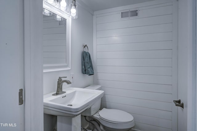 half bathroom with toilet, visible vents, and a sink