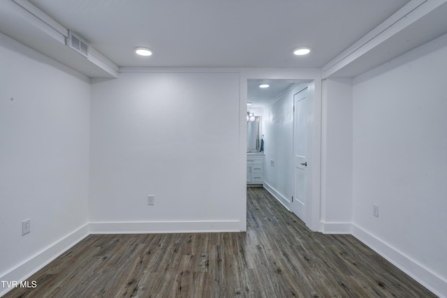 empty room featuring dark wood-style flooring, visible vents, and baseboards