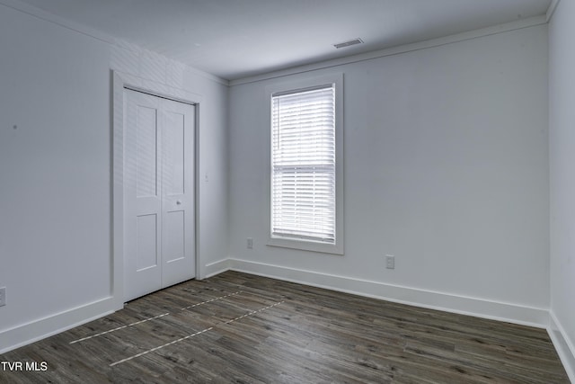 unfurnished bedroom featuring dark wood-style flooring, a closet, and baseboards