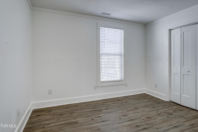 unfurnished bedroom featuring dark wood-style floors, a closet, visible vents, and baseboards