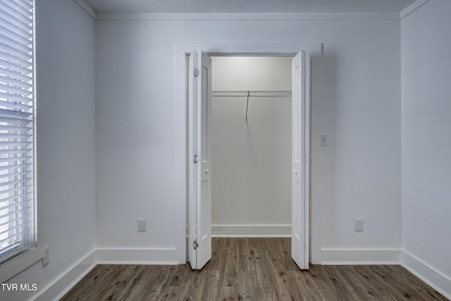 unfurnished bedroom with a closet, baseboards, and wood finished floors