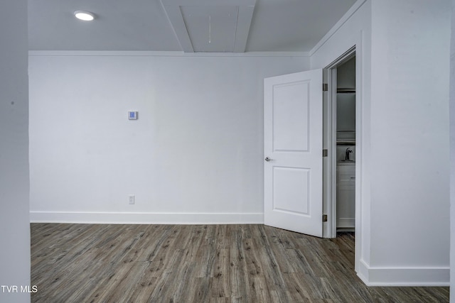 spare room with attic access, baseboards, and wood finished floors