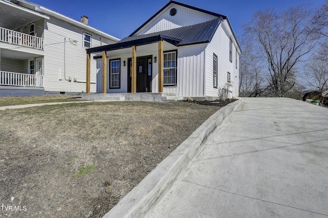 view of front facade featuring a porch, metal roof, and board and batten siding