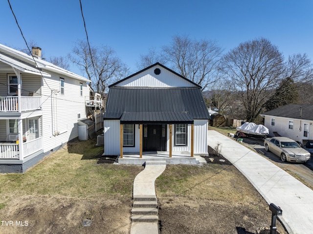 view of front of property with covered porch, metal roof, a front lawn, and central air condition unit