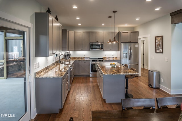 kitchen featuring stainless steel appliances, dark stone counters, a sink, and gray cabinetry