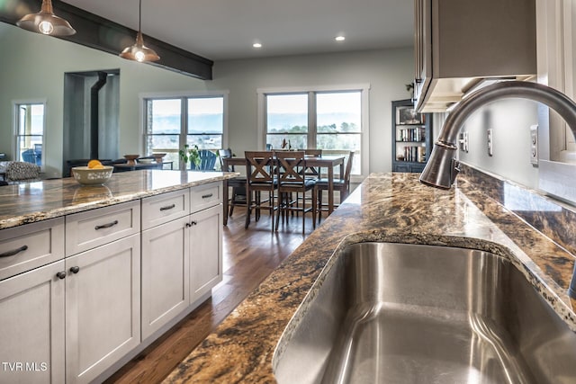 interior space featuring pendant lighting, recessed lighting, dark wood-type flooring, a sink, and dark stone countertops