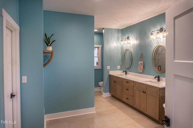 bathroom with baseboards, a sink, toilet, and double vanity