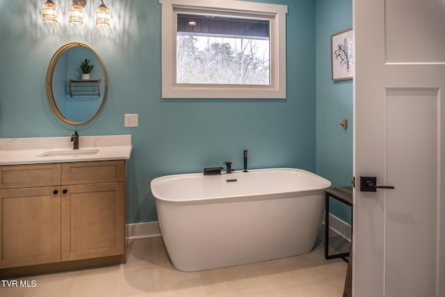 full bath with a soaking tub, vanity, and baseboards