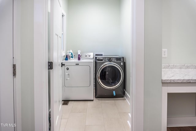 clothes washing area featuring laundry area, light tile patterned floors, and independent washer and dryer