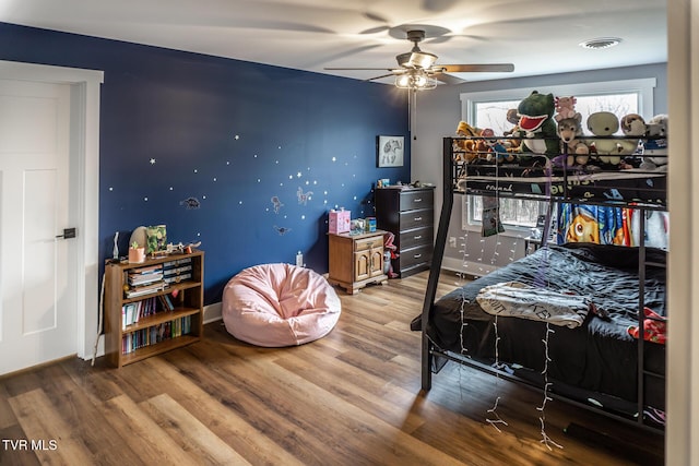 bedroom featuring visible vents, ceiling fan, baseboards, and wood finished floors