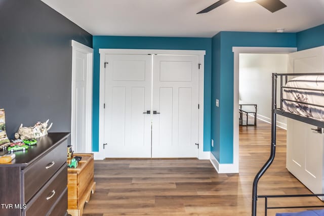 bedroom with ceiling fan, a closet, wood finished floors, and baseboards