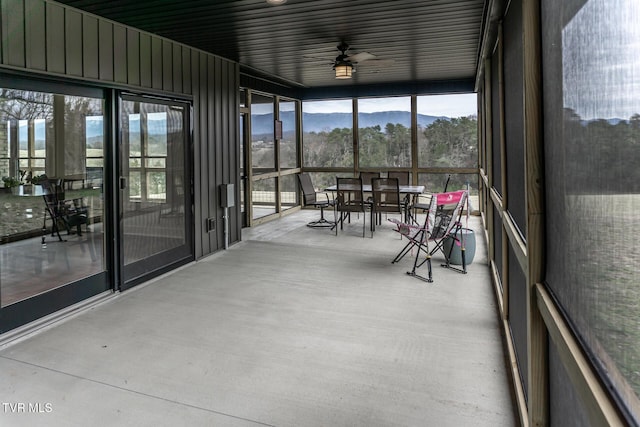 unfurnished sunroom featuring a mountain view and a ceiling fan