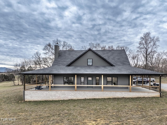 rear view of property with roof with shingles, a lawn, and a chimney