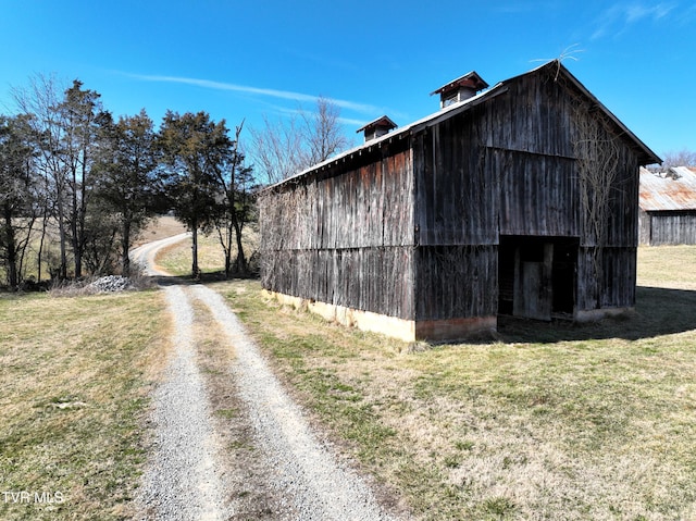 view of barn with driveway and a lawn