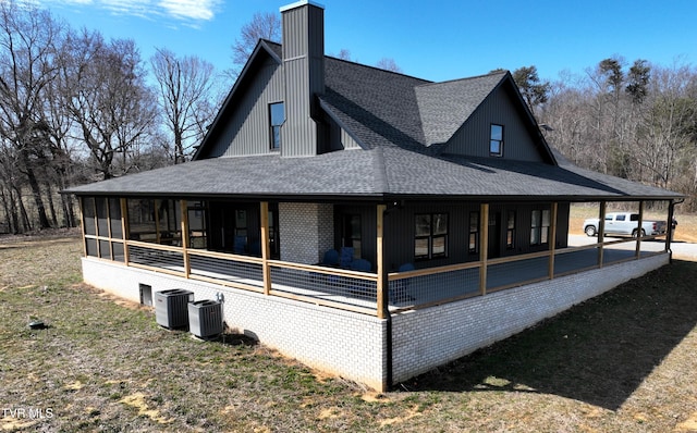 view of side of property with a sunroom, a shingled roof, and cooling unit