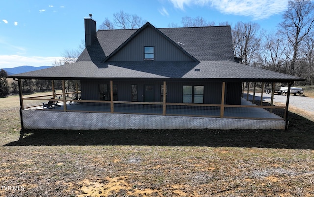 back of house with a shingled roof and a chimney