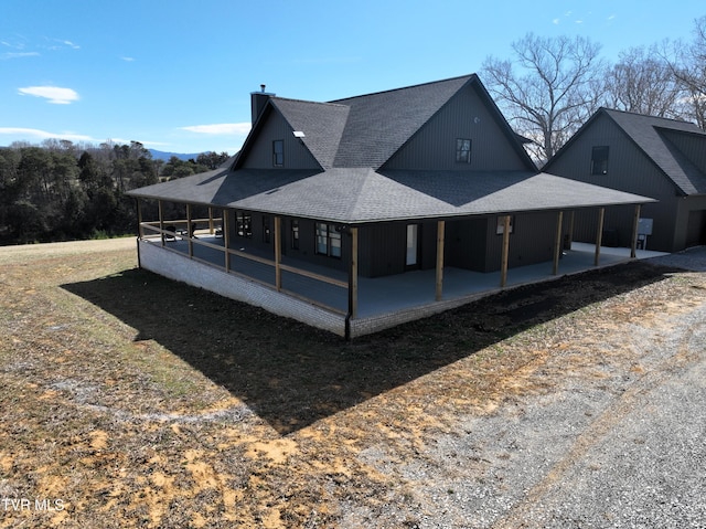 rear view of property featuring a shingled roof, a chimney, and a patio